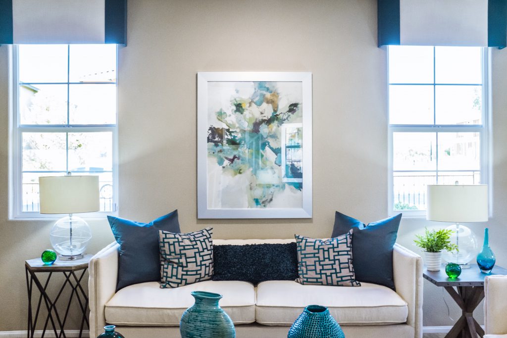 couch between two windows with art hanging above pillows