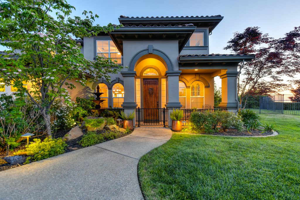 beautiful home for sale with lights on early evening arched portico wooden door