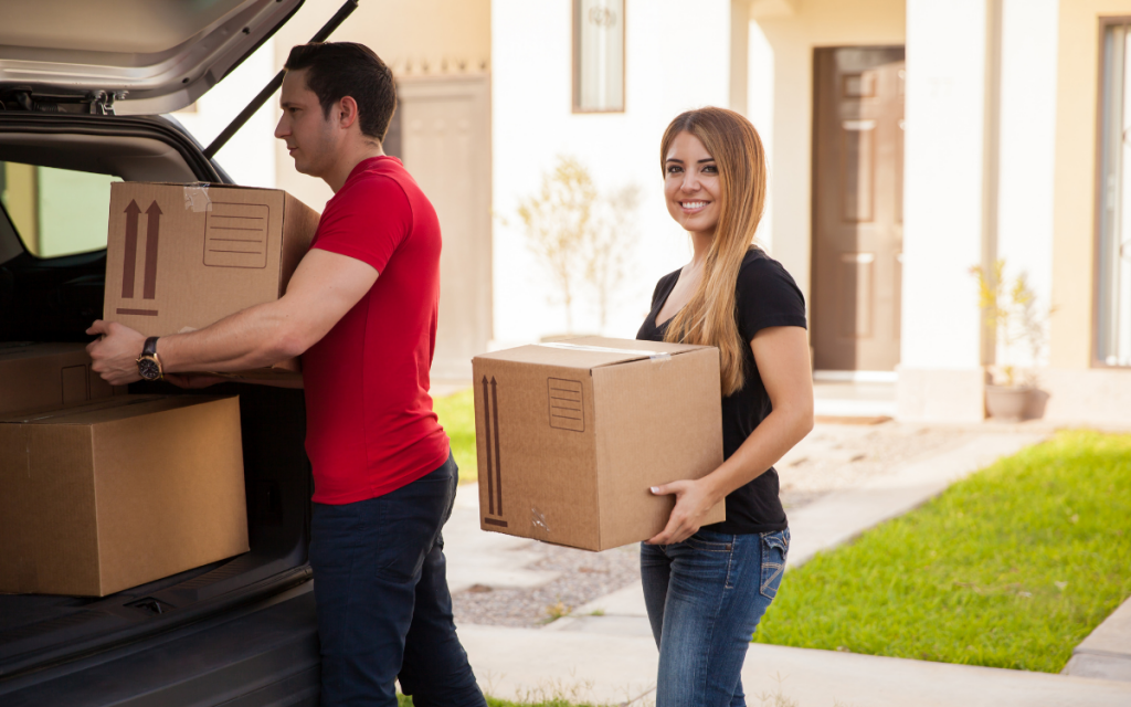 happy couple moving out carrying cardboard boxes