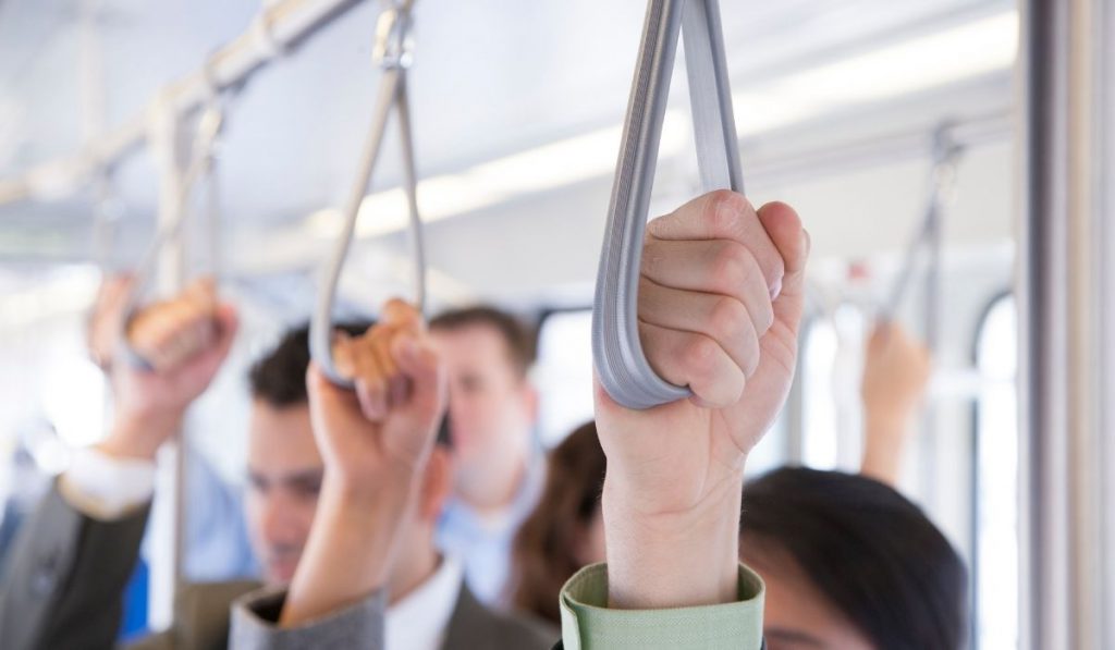 commuters in the bus holding the hanging strap on their way to work