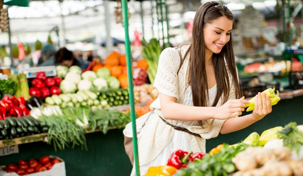 a lady buying fresh produce at the farmers market