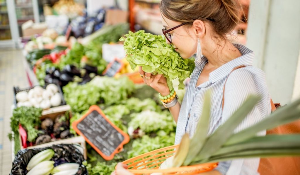 girl smelling a lettuce at a sunday market