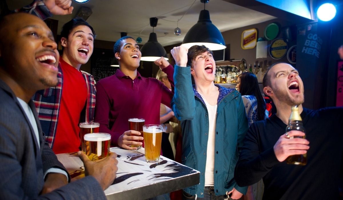 guys at a sports bar enjoying drinks and watching a game