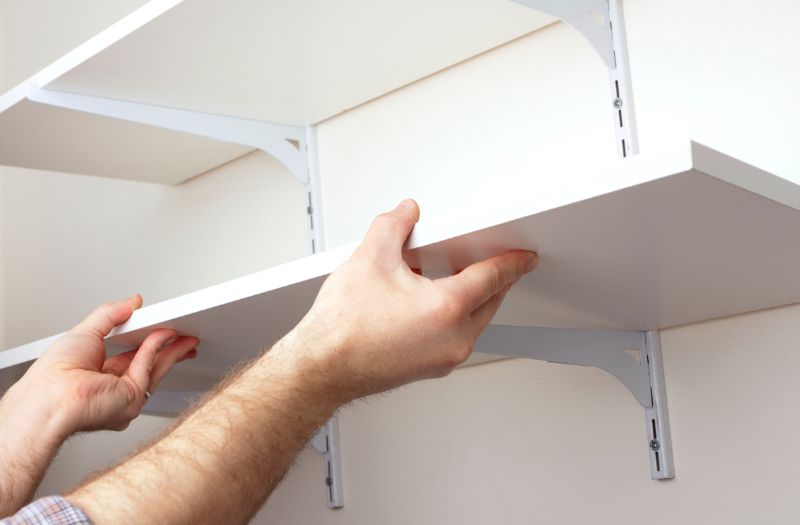 man putting open shelves on the wall