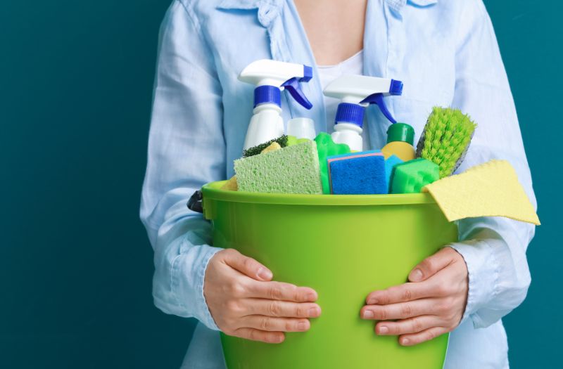 woman holding a bucket of cleaning supplies
