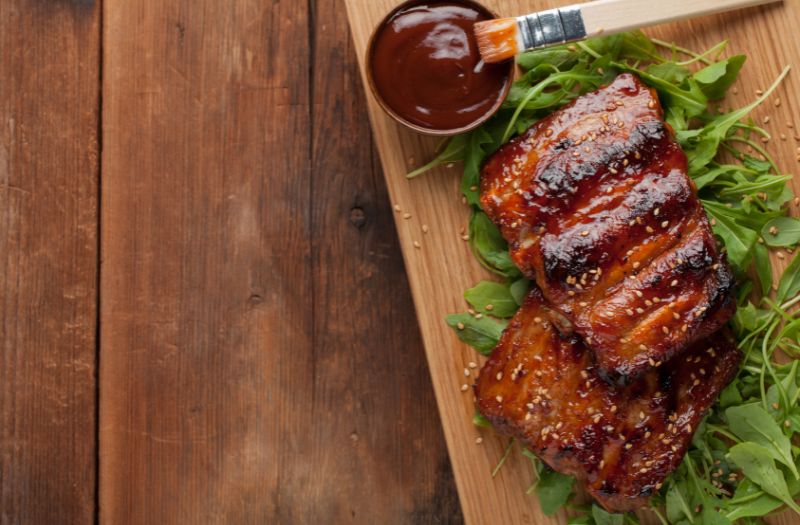 bbq smoked ribs on a wooden board with a sauce