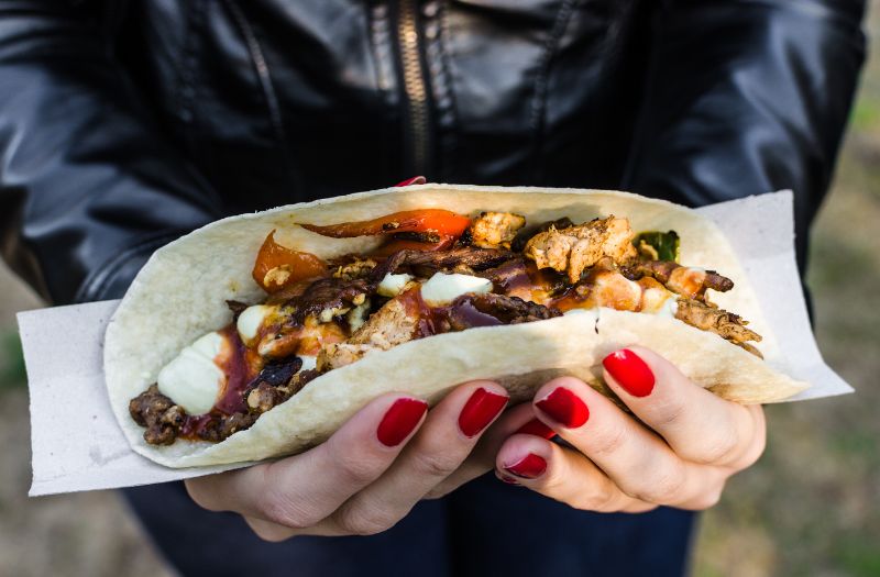 woman holding yummy tacos at a square market