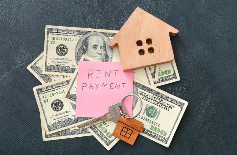 cash for the rent payment, keys and a small wooden shaped house on the table